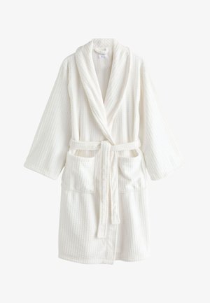 Peignoir blanc à texture gaufrée, col châle, manches longues, deux poches avant et ceinture en tissu nouée à la taille.
