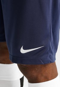 Navy blue Nike shorts made of smooth, lightweight fabric. Features a white embroidered logo on the lower leg and a simple, functional design.