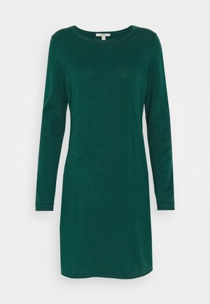 Tmavě zelené pletené šaty s dlouhým rukávem do délky ke kolenům, s kulatým výstřihem a žebrovanými manžetami, položeny na bílém pozadí.