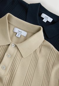 Kaks keskmise suurusega NEXT kaubamärgiga polosärki, üks beež ja üks must, millel on nähtaval kraed, nööbiplastrid ja kangatekstuuri detailid.