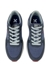 Zapatillas de malla grises con cordones blancos, tela texturada y un acento rojo en la suela. Forma curva y cuello acolchado para mayor comodidad.