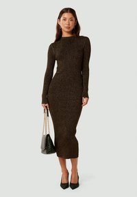 Vestido comprido e ajustado em tecido de malha escura com nervuras e com detalhes metálicos. Apresenta mangas longas, um decote alto e uma saia de comprimento midi.