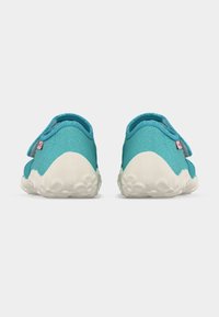 Ζευγάρι τυρκουάζ αθλητικά παπούτσια με υφασμένα λευκά πέλματα, σε οπίσθια όψη σε λευκό φόντο.