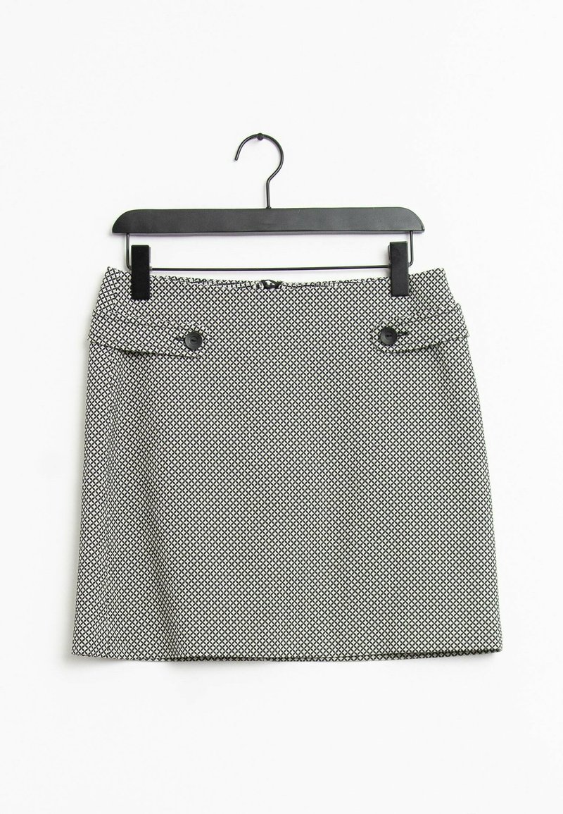 Jupe pour femme à motif noir et blanc avec des pans boutonnés à l'avant, suspendue sur un cintre noir contre un fond blanc.