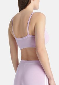 Fialová sportovní podprsenka s nastavitelnými ramínky a bílými lemovkami. Měkká, elastická tkanina navržená pro pohodlí a oporu.
