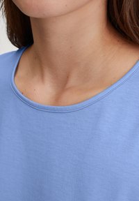 Lichtblauwe katoenen t-shirt met een ronde hals. De stof heeft een zachte textuur en een subtiel, fijn geribbeld patroon.