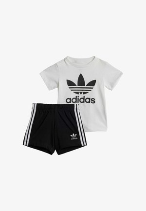 Îmbrăcăminte pentru copii Adidas care include un tricou alb cu logo negru și șorturi negre cu dungi albe pe lateral și logo pe margine.