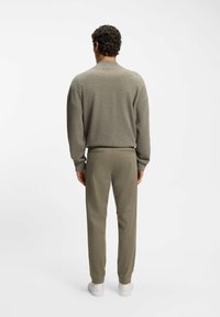 Grå striktrøje med sænkede skuldre, parret med olivengrønne tapered bukser. Outfittet er fuldendt med hvide sneakers.