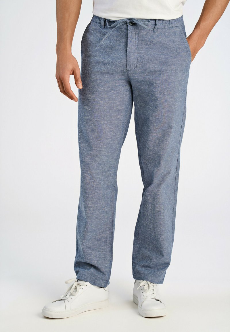 Jasnoniebieskie, teksturowane spodnie z elastycznym paskiem i sznurkiem, z bocznymi kieszeniami i luźnym krojem. Zestawione z białymi sneakersami.