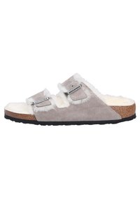 Sandalo grigio in suede con fodera in ecopelliccia bianca, due cinturini regolabili e suola in sughero. Suola esterna in gomma nera per una migliore trazione.
