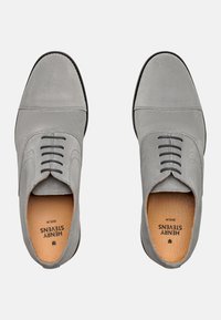 Chaussures en daim gris avec un bout arrondi, six œillets et un design cousu. Présente des accents texturés et une doublure intérieure lisse.