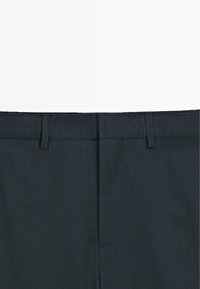 Pantaloni grigio scuro con una superficie di tessuto liscia, caratterizzati da un cinturino piatto e un delicato dettaglio di cucitura. Design pulito, senza motivi o elementi hardware visibili.