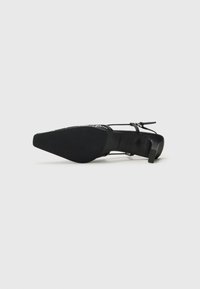 Black high-heeled shoe with a pointed toe, textured material, thin straps, and a slim heel. The sole is smooth with minimal detailing.