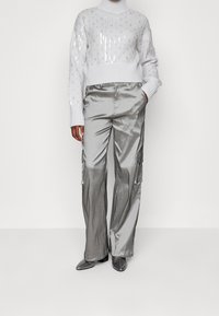 Pull à col roulé court gris clair avec sequins ; pantalon cargo métallique argenté ; bottines grises à talons pointues.