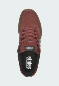 Zapatilla de ante burdeos con superficie texturizada, diseño de cordones, caja de dedos perforada y plantilla negra con la marca "etnies".