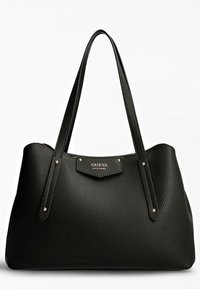 Sac fourre-tout texturé noir avec deux longues anses, présentant une petite plaque en métal doré inscrite "GUESS EST 1981" à l'avant.