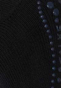 Tejido negro de punto con un patrón texturizado, que presenta cuentas brillantes de color azul marino acentuando el lado, mejorando el interés visual.