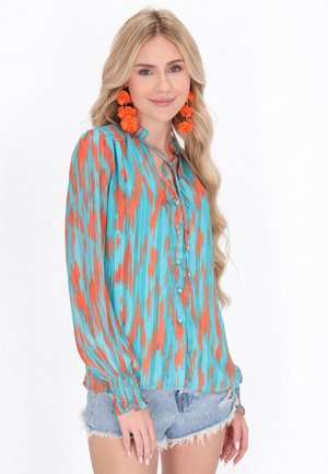 Mehrfarbige Bluse mit einem türkis-orangefarbenen Muster, langen Ärmeln mit Knopfmanschetten und einem gebundenen Ausschnitt.