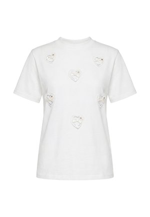Hvid T-shirt med korte ærmer med seks små blonder hjertepatches, hver med en sløjfe og lille blomsterdetalje foran.