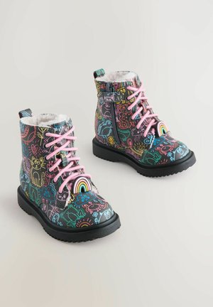 Schwarze Stiefeletten aus Kunstleder mit bunten Kritzelmustern, pinken Schnürsenkeln, weißem Futter und einem Regenbogenelement an der Zehenpartie. Reißverschluss an der Seite.