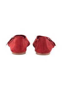 Zapatillas rojas de ante con forma redondeada, textura suave y un diseño minimalista, que cuentan con una pequeña correa decorativa a cada lado.