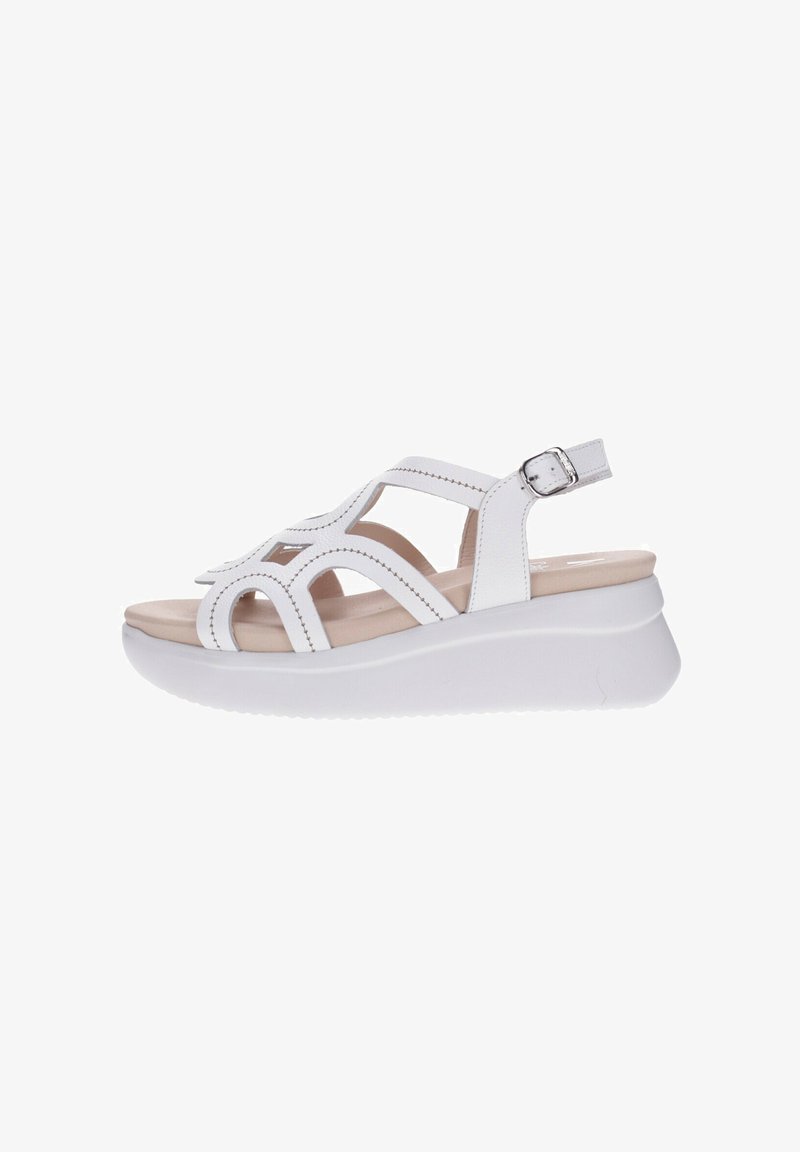 Sandalia de cuña blanca para mujer con tiras recortadas, cierre de hebilla, plantilla beige acolchada y suela gruesa, vista lateral sobre fondo blanco.