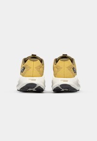 Sport shoes featuring a yellow upper with textured finish, cushioned white midsole, and black rubber outsole. Rear loop detail visible.