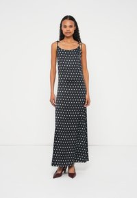 Melna maksi kleita ar baltiem punktiņiem, plānām lencītēm un sānu šķēlumiem, izgatavota no mīksta auduma. Raksturīga brīva piegriezuma un baltie punktiņi.