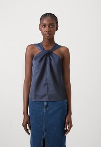 Marine satin uten ermer topp med vridd frontdetalj, kombinert med en jeansskjørt med frontsplitt og en tettsittende, rett design.