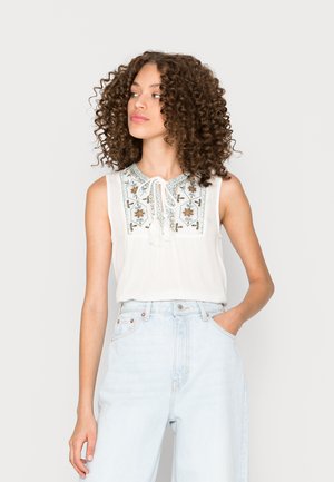 Blusa bianca senza maniche con colletto annodato e complessa ricamata floreale blu e arancio sul colletto; tessuto leggero.