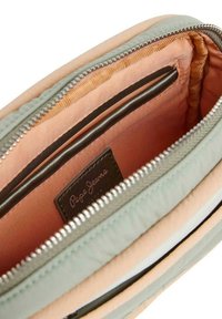 Pochette Pepe Jeans con una fodera interna color pesca, tessuto esterno verde, zip argentata e un'etichetta interna. Texture liscia con una forma strutturata.