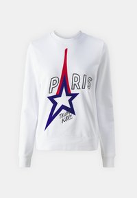 Hvit genser med grafikk av Eiffeltårnet i rødt og en blå stjerne. Tekst "PARIS" over og "TEAM KARL" under i svart. Klassisk rund hals-design.