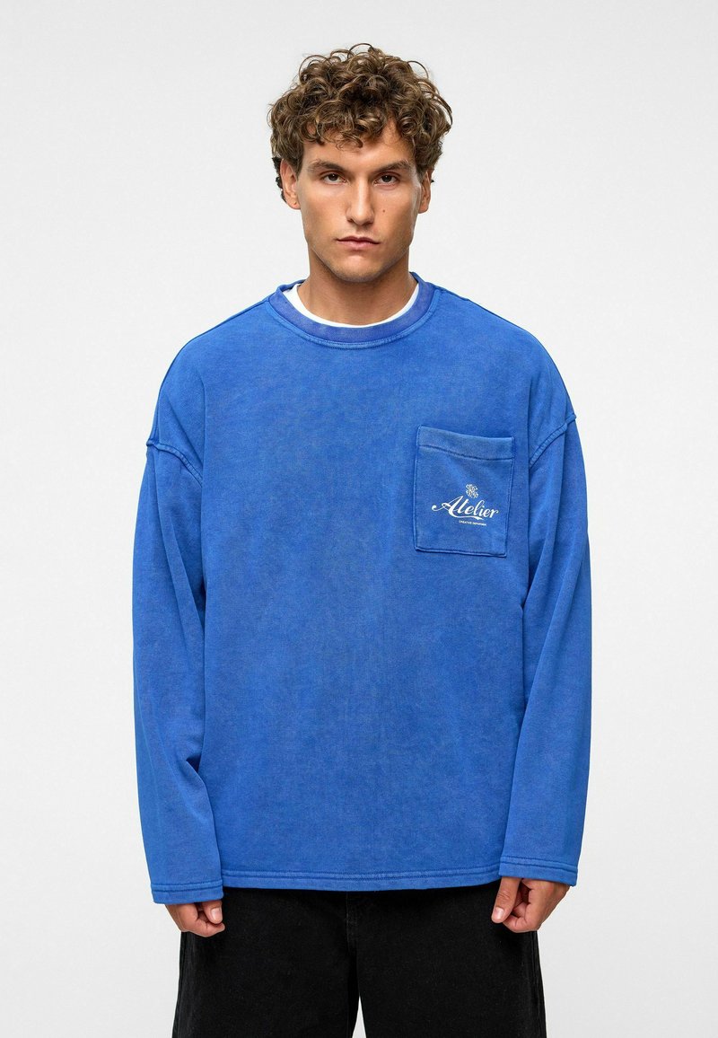 Blauw overhemd met lange mouwen, gemaakt van zachte stof, met een borstzak, voorzien van een gestructureerde uitstraling en geborduurd logo op de zak.