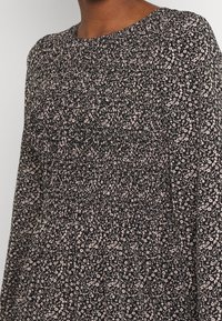 Schwarzes Kleid aus Stoff mit floralem Muster in Rosatönen, mit langen Ärmeln und gerafften Details an der Taille. Rundhalsausschnitt.