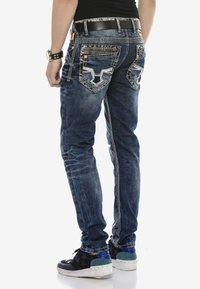 Blaue Denim-Jeans im Slim-Fit mit dekorativer Naht, zwei Gesäßtaschen und einer kontrastierenden Naht entlang des äußeren Beins.