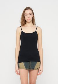 Μαύρο αμάνικο τοπ με λεπτές τιράντες, κατασκευασμένο από απαλό ύφασμα. Ο σχεδιασμός είναι εφαρμοστός και απλός, συνδυασμένος με μια μίνι τζιν φούστα.