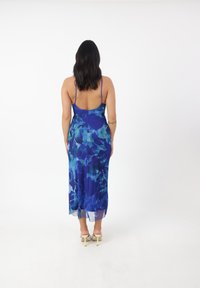 Blå blomster maxi kjole med tynde stropper, der har et tætsiddende liv og en flowy nederdel. Stoffet har et struktureret, let udseende.