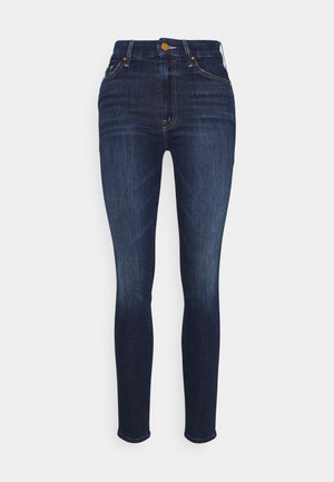 Jeans skinny bleu foncé à taille haute avec légère décoloration sur les cuisses, poches avant, passants pour ceinture et fermeture bouton à la taille.