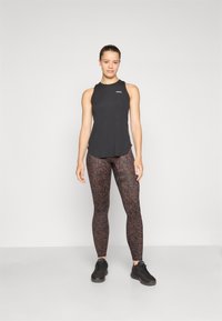Black sleeveless athletic top paired with brown leopard print leggings, featuring a textured design and complemented by black sports shoes.