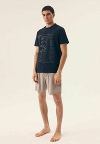 Granatowa koszulka z napisem "TYLKO DLA LOKALNYCH" oraz designem palmowym; zestawiona z jasnoszarymi szortami o miękkiej teksturze i luźnym kroju.