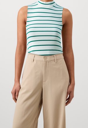 Mouwloze witte top met groene horizontale strepen, gecombineerd met beige wijde broek met hoge taille bij een persoon.