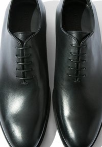 Chaussures habillées en cuir noir avec une finition lisse, bout rond et fermeture à lacets à six œillets. Présente un design minimaliste sans embellissements.