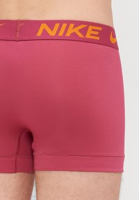 Nike muške bokserice u jednobojnoj boji tamnocrvene s narančastim logom na pojasu. Mekani, elastični materijal i prilagođeni kroj.