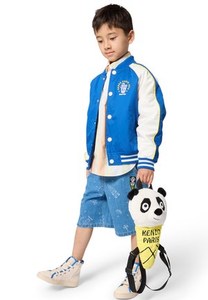 Blauw-witte bomberjack met geborduurd logo, licht shirt, spijkershorts met patronen en een pluche rugzak met pandathema.