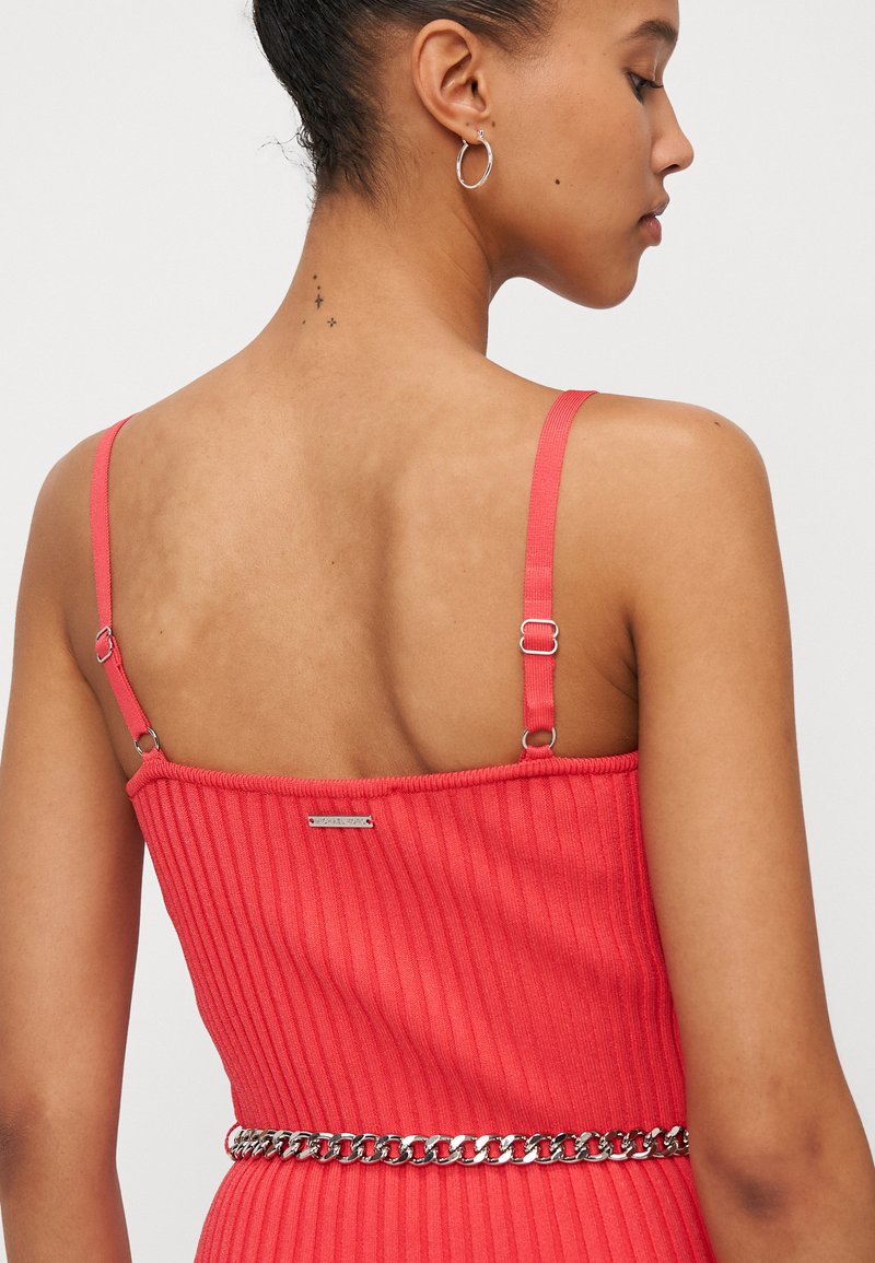 Rotes geripptes Kleid mit dünnen verstellbaren Trägern und einem silbernen Kettengürtel. Verfügt über ein dezentes Markenetikett auf der Rückseite. Geschmeidige Oberfläche.