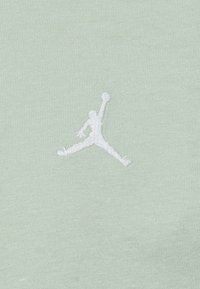 Svetlozelená krátkopytová košeľa z mäkkej bavlny s bielym vyšitým logom Jumpman na prednej strane.