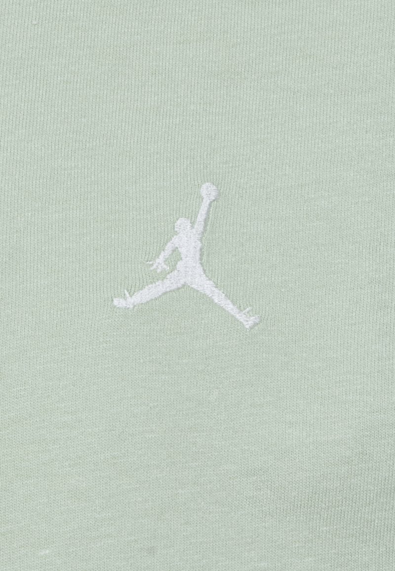 Camisa de manga corta verde claro hecha de algodón suave, con un logo Jumpman bordado en blanco en la parte delantera.