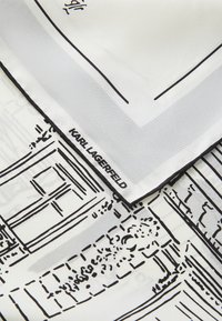 Fehér selyemsál fekete vonalrajzzal, amely épületeket ábrázol. Fekete szegéllyel és "KARL LAGERFELD" címkével az alsó sarokban.