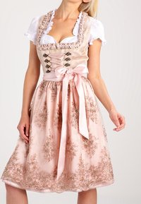 Dirndl z dopasowaną beżową górą, sznurowanym przodem i bufiastymi białymi rękawami; różowa spódnica z haftem kwiatowym i satynową wstążką.