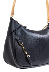 Borsa a spalla in pelle nera texture con tracolla beige e chiusura decorativa in metallo dorato su sfondo bianco.